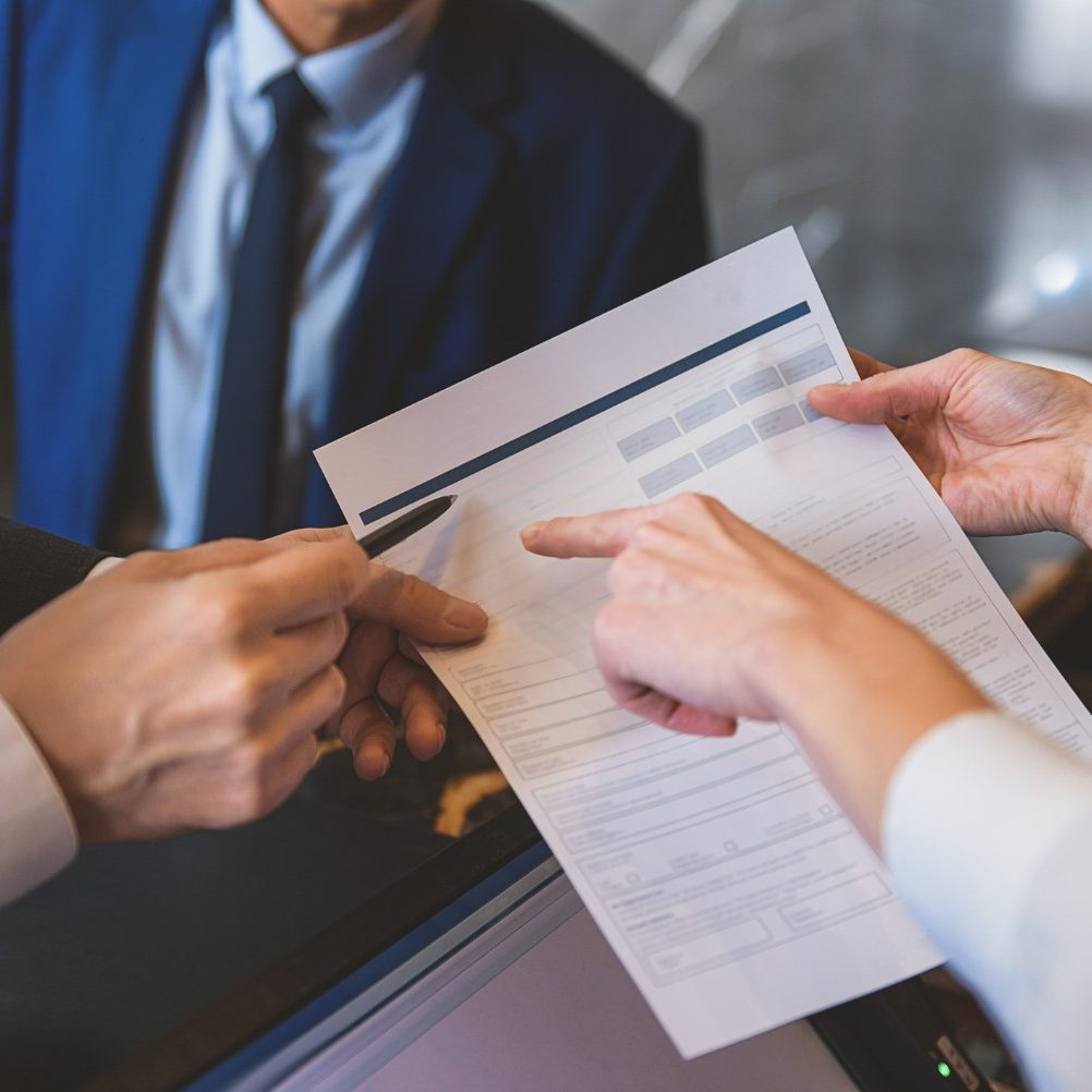 a-succesful-hotel-sales-manager-holding-a-contract-and-pointing-to-where-the-client-should-sign.